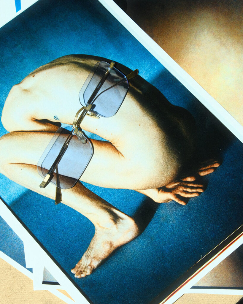 Getönte Brille liegt auf einem Fotoabzug mit einem hockenden Körper